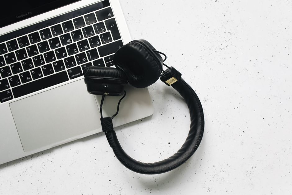 Overhead view of a laptop and headphones on a stylish marble background.